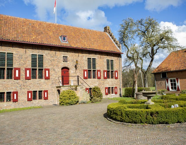 Voorzijde historische havezate met rood-witte luiken, voorplein en bijgebouw op landgoed Hagen