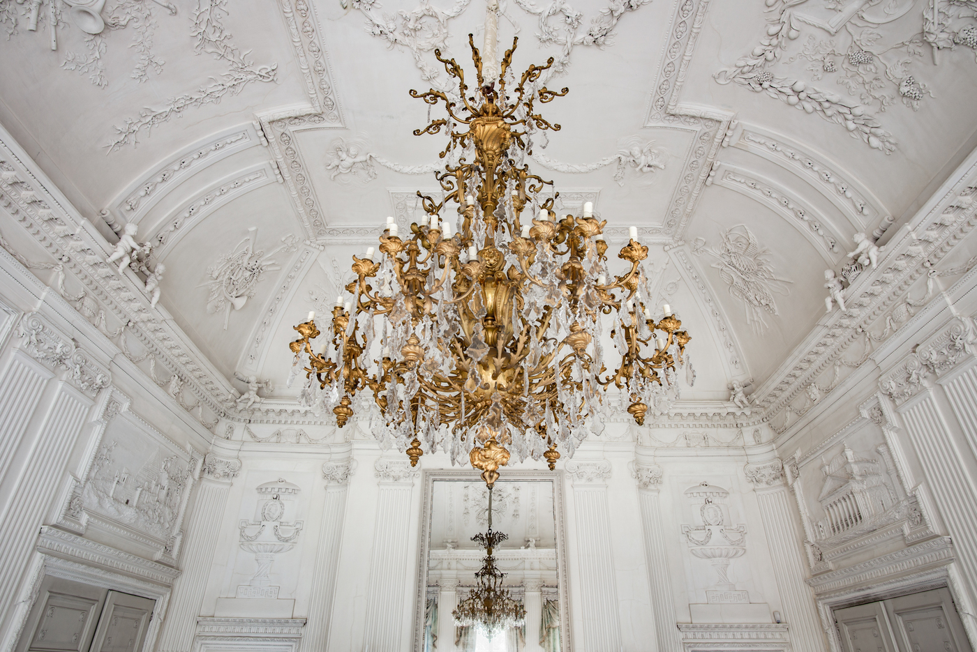 Kasteel Biljoen; goudkleurige kroonluchter met kristallen in de witte stuczaal