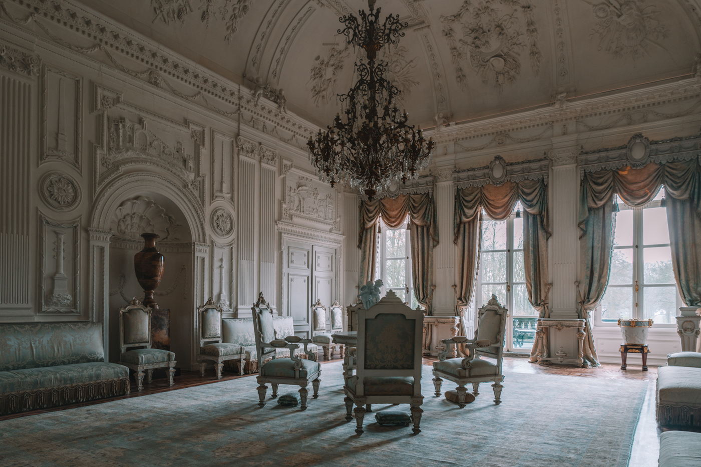 Kasteel Biljoen; witte stuczaal met kroonluchter en antiek meubilair