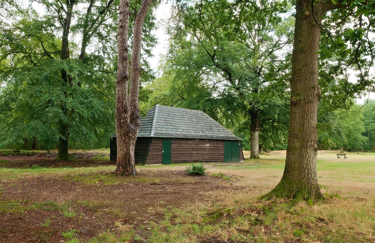 Houten schuur met bomen en bankjes op het Erf van Daendels, gelegen op landgoed De Dellen en Heerder Sprengen.