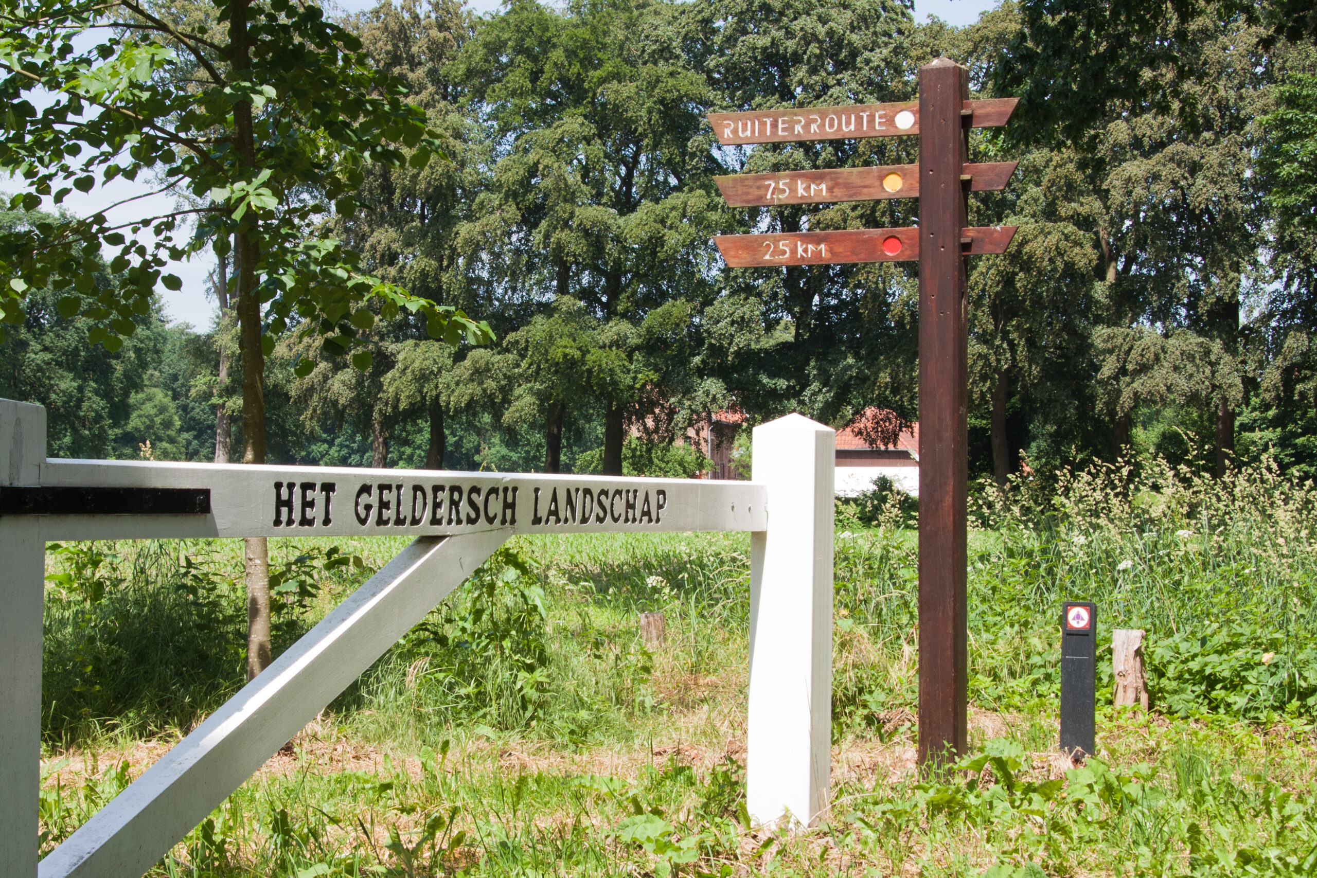 Landgoed Hagen; een wit toegangshek van Geldersch Landschap en Kasteelen en een houten wegwijzer.