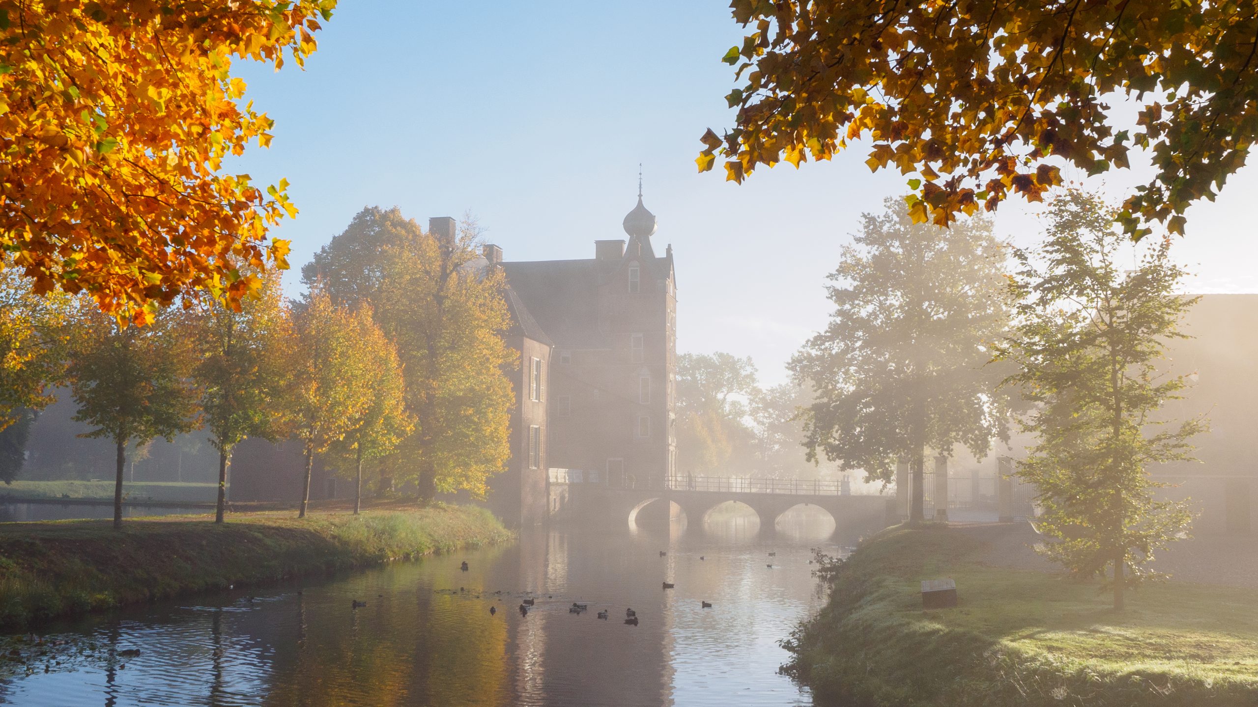 Bomen langs de gracht van kasteel Cannenburch getooid in herfstkleuren.