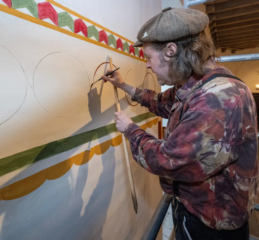 Marius Bruijn, specialist in middeleeuwse muurschilderingen, beschildert een muur in de grote zaal van kasteel Ammersoyen met een decoratieve band en een gordijn-imitatie.