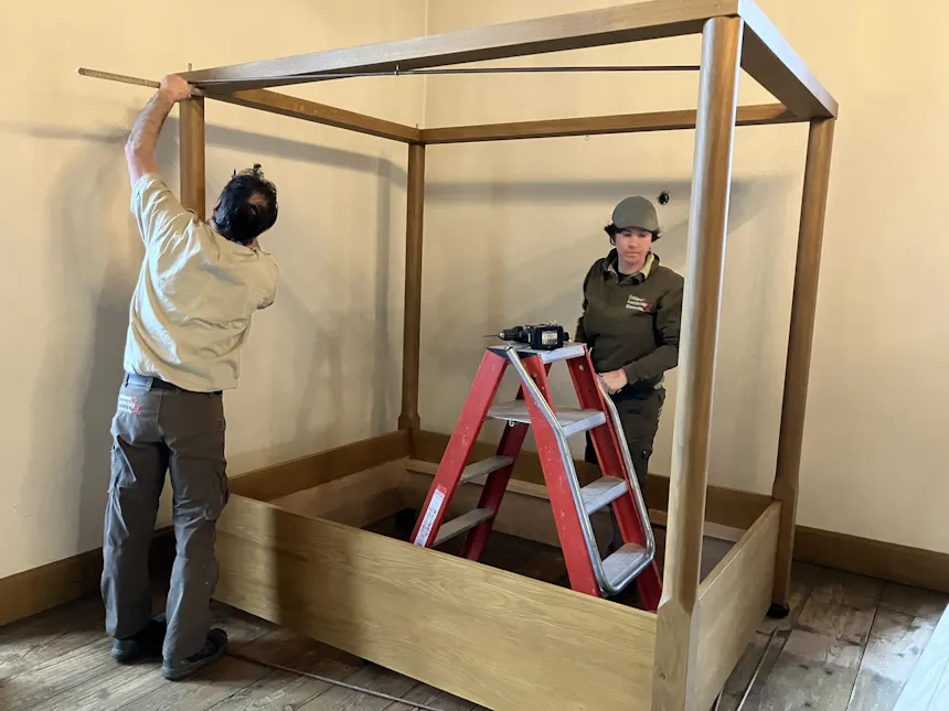 Twee medewerkers van GLK zijn bezig met het bouwen van een replica van een 17e-eeuws eikenhouten hemelbed in de grote torenkamer van kasteel Ammersoyen.